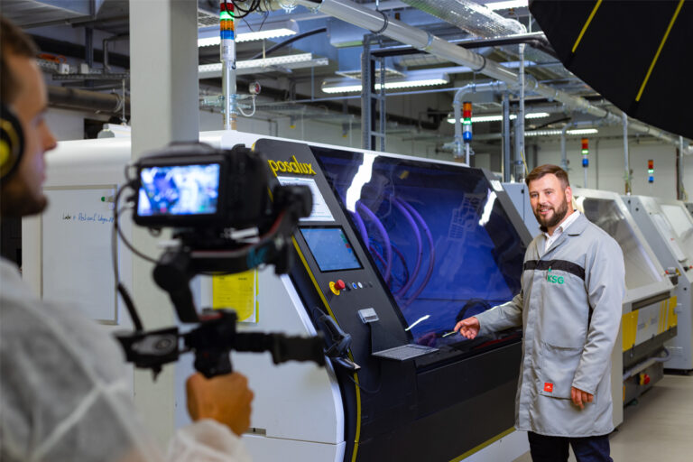 Herr Robert Jungk zeigt auf eine Borhmaschine während ein Kameramann das Geschehen aufzeichnet.